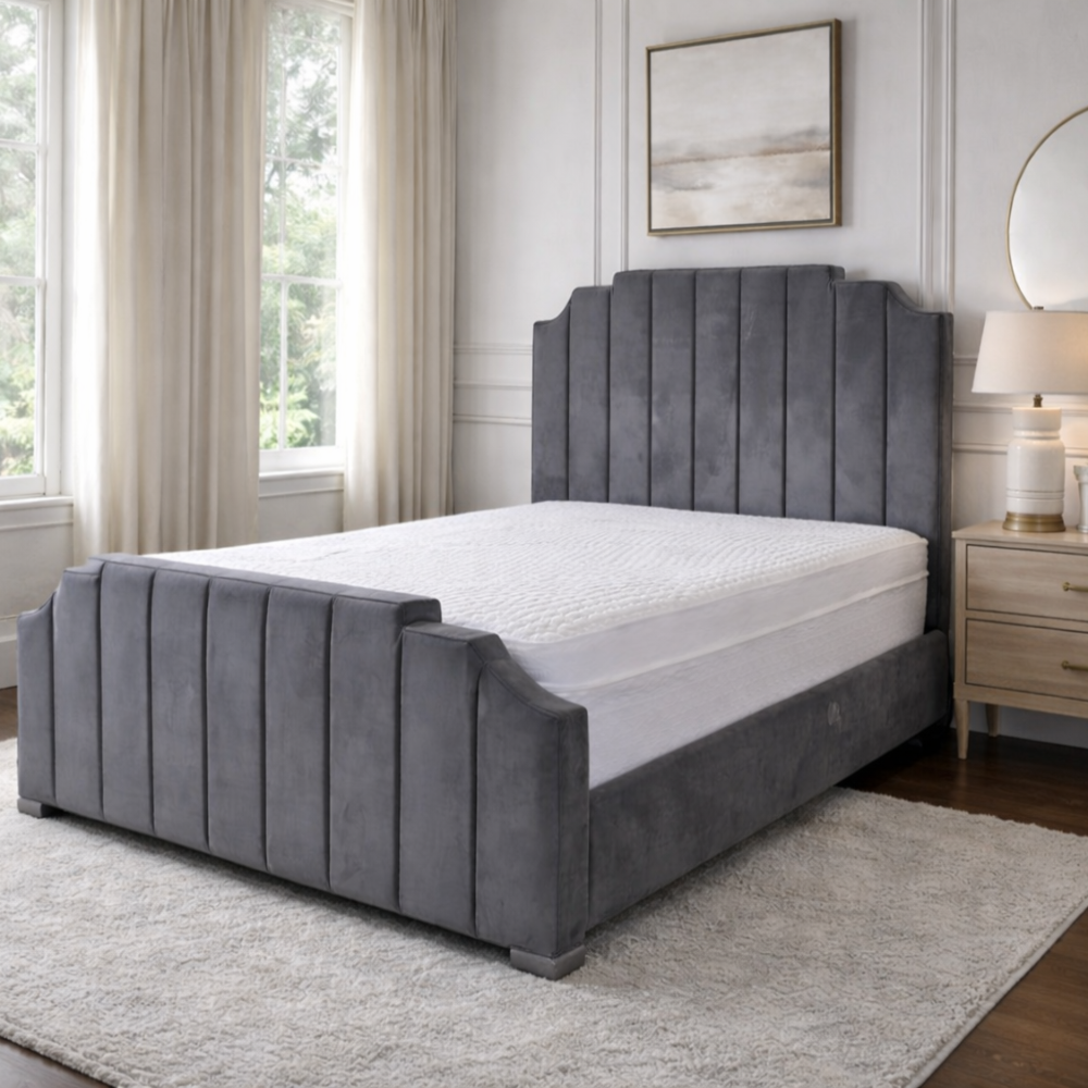 Gray upholstered bed in a bedroom with a lamp, mirror, and decor.